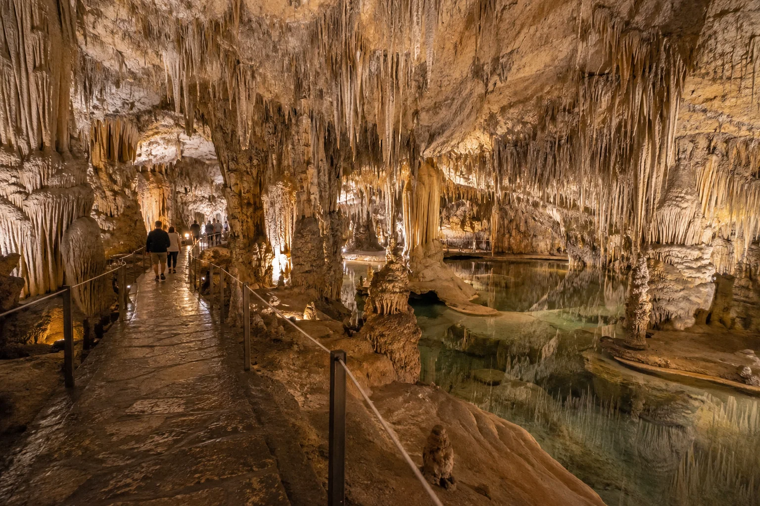 Sendero iluminado entre formaciones de estalactitas y estalagmitas en las Cuevas del Drach